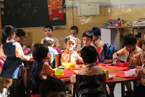 Group of young children sitting in their colourful classrooms, enjoying activities.
